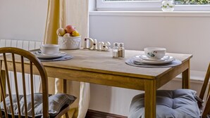 A dining table with a bowl of fruit, salt and pepper shakers, and two cups on a wooden table with a chair in front. - 1 Bed in Haltwhistle (oc-nb556) (Haltwhistle)