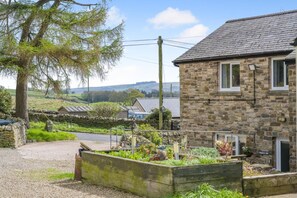 A stone house with a garden, a stone wall, and a view of the countryside. - 3 Bed in Haltwhistle (oc-nb558) (Haltwhistle)
