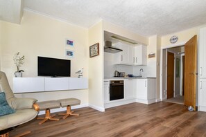 A compact living space with a sofa, a TV, a dining area, and a kitchen. - 2 Bed in Saundersfoot (oc-pw9131) (Saundersfoot)
