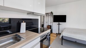 Cocina compacta con lavamanos, cocina y un televisor de pantalla plana montado en la pared.
