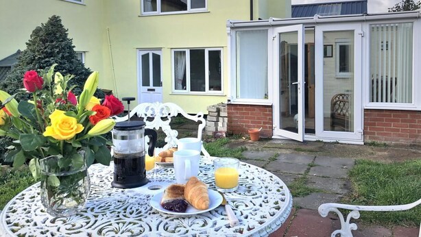 A patio with a table set for breakfast, including a coffee maker, croissants, and juice. - 2 Bed in Aldeburgh (oc-marsh) (Friston)