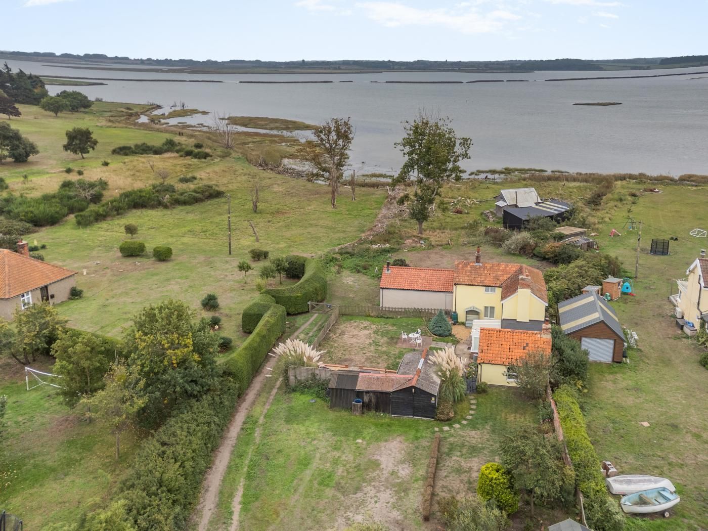 A residential area with houses, a grassy field, and a body of water in the background.