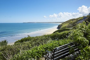 A coastal landscape with a bench, a beach, and a cliff. - 2 Bed in St. Ives (oc-p00693) (Carbis Bay)