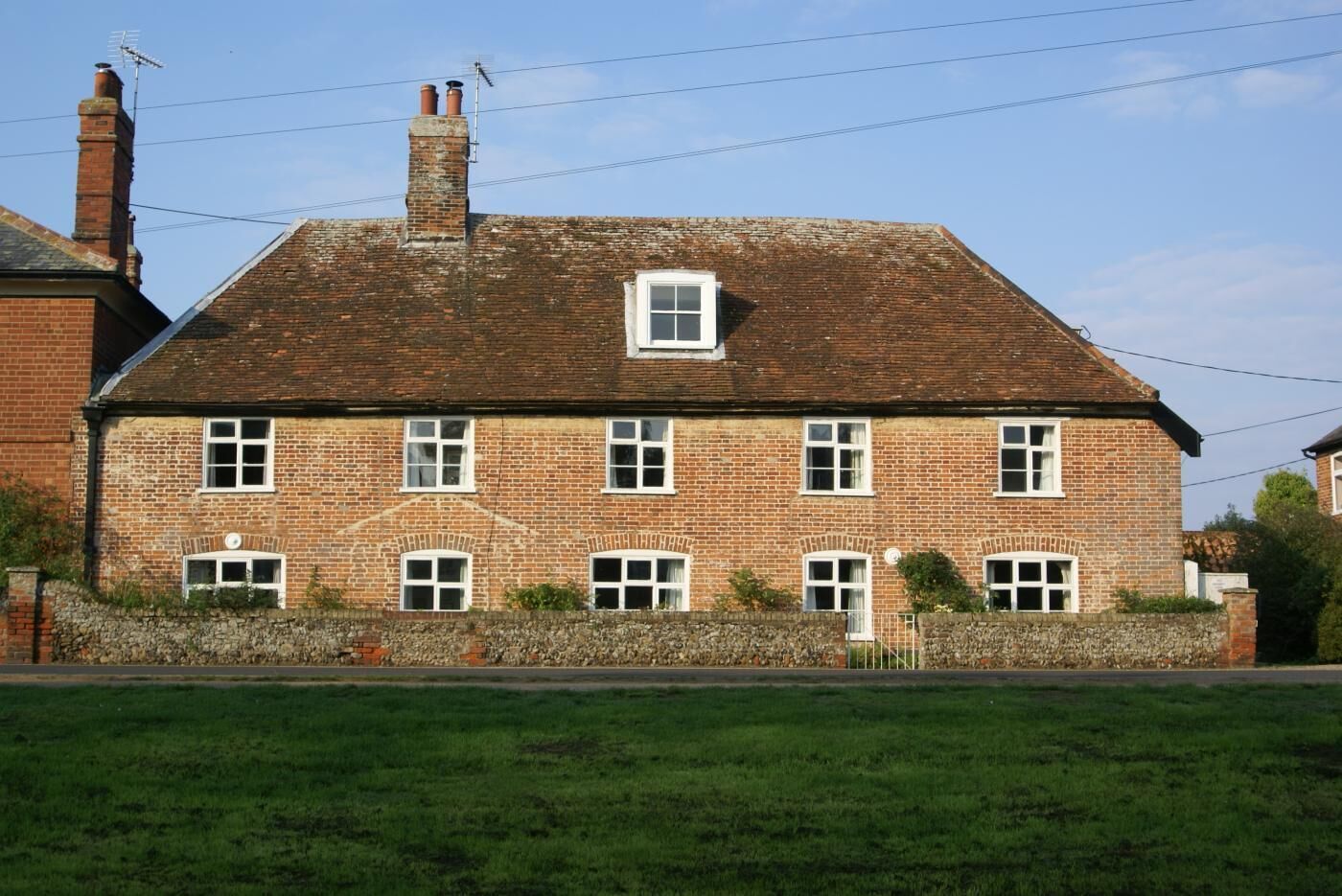 A brick building with a pitched roof, multiple windows, and a small door.