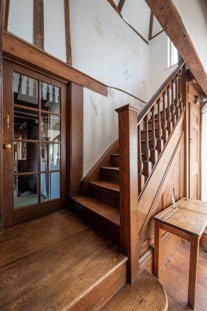 Un escalier en bois avec une porte en verre qui mène à une pièce où se trouve une bibliothèque.