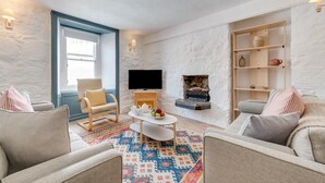 A living room with a fireplace, a television, and a bookshelf. - 2 Bed in St Ives (oc-pmho10) (St Ives)