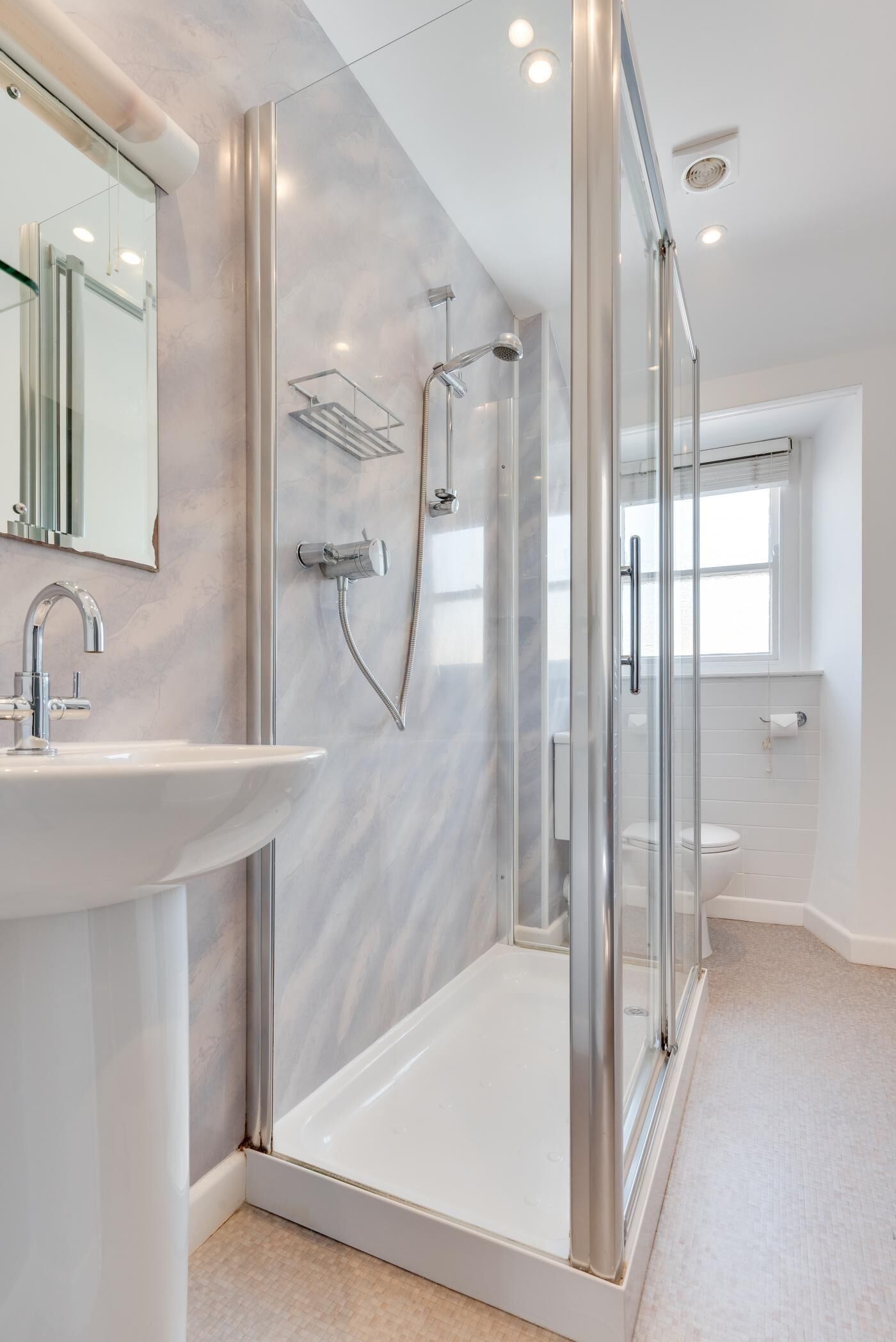 A modern bathroom with a glass-enclosed shower, a white sink, and a large mirror.