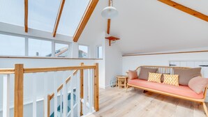 A spacious loft with a wooden staircase, a cozy sofa, and a small table. - 2 Bed in St Ives (oc-pmho10) (St Ives)
