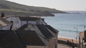 A coastal town with buildings overlooking the sea, a beach, and a hilly landscape in the background. - 2 Bed in St Ives (oc-pmho10) (St Ives)