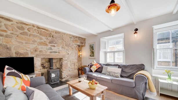 Una sala de estar acogedora con una pared de piedra, una chimenea, un sofá, una mesa de centro y un televisor.