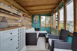 A cozy room with wicker furniture, a wooden ceiling, and a view of the city. - 3 Bed in St Ives (oc-twp21) (St Ives)