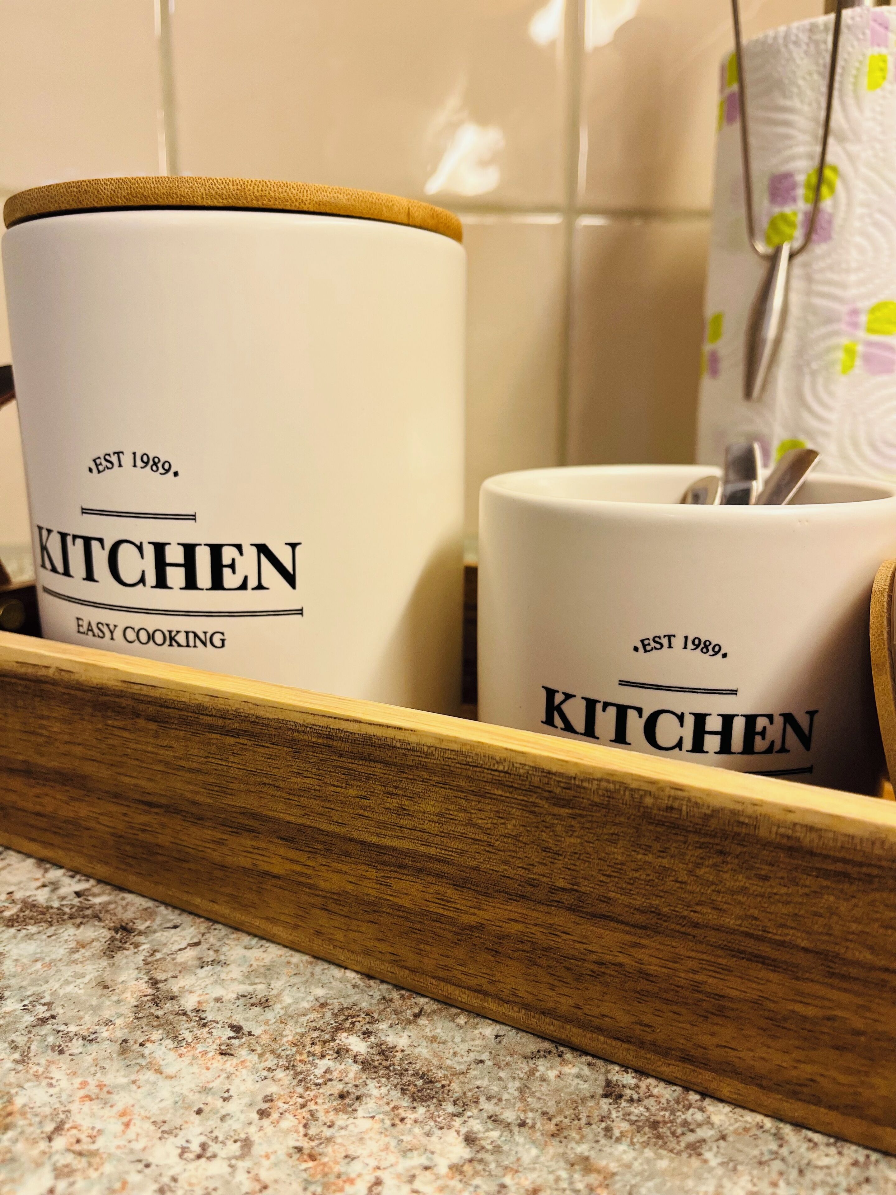 A kitchen utensil holder with two white containers labeled 'KITCHEN EASY COOKING EST 1989.'