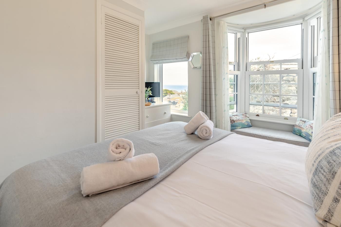A hotel room with a bed, a window with a view, and a white wardrobe.