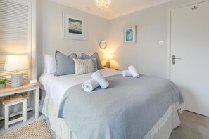 A neatly arranged bedroom with a bed, pillows, a bedside table with a lamp, and a door. - 2 Bed in St Ives (oc-albt02) (St Ives)