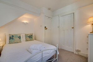 A bedroom with a bed, two doors, a bedside lamp, and a wall-mounted light fixture. - 1 Bed in St Ives (oc-quayst) (St Ives)
