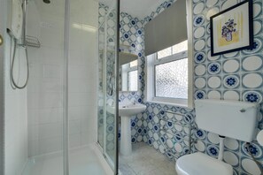A bathroom with a shower, sink, toilet, and a window with decorative tiles. - 1 Bed in St Ives (oc-quayst) (St Ives)