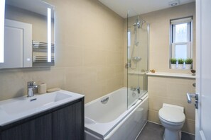 Une salle de bain moderne avec une douche à parois de verre, une baignoire blanche, des toilettes et un meuble-lavabo avec un miroir.