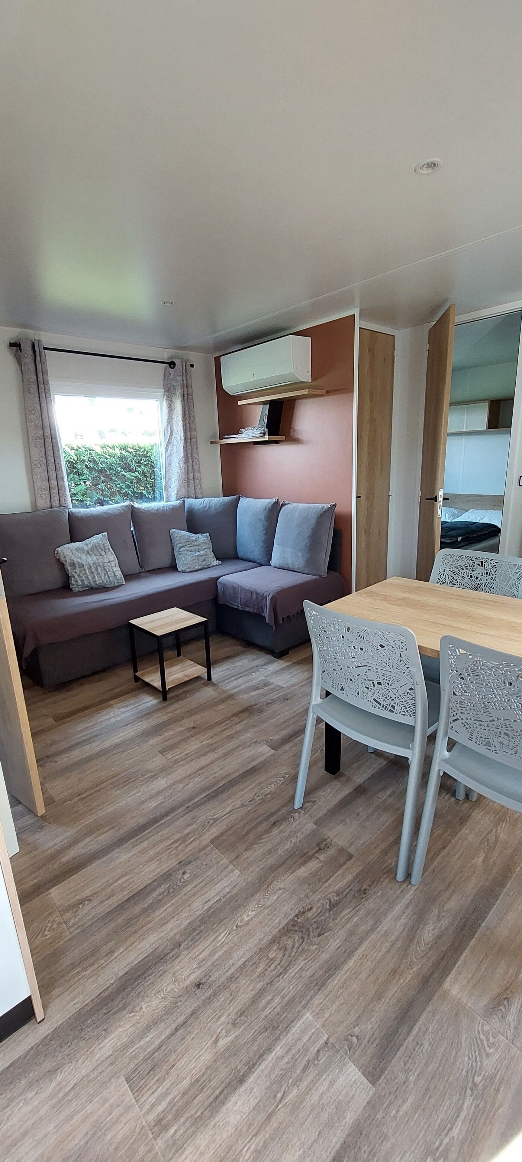 Un salon moderne comprenant un canapé, une petite table et un coin repas avec des chaises.