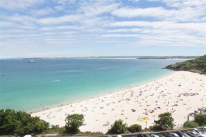 A beach with numerous umbrellas and people. - 2 Bed in St Ives (oc-lookcv) (St Ives)