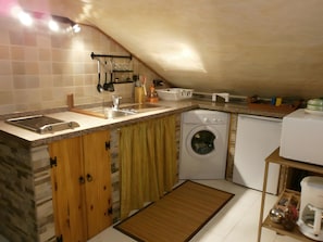 Cocina compacta con lavadora integrada, un lavamanos y armarios de madera.