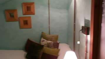 Una stanza con un letto, un comodino con una lampada e tre quadri quadrati appesi al muro.