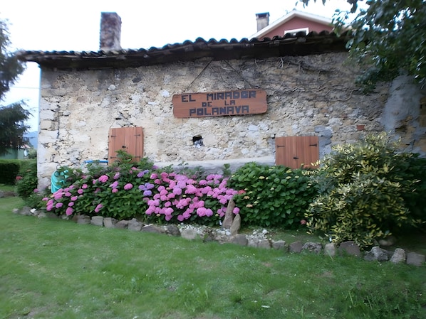 Un edificio rústico de piedra con un letrero de madera que dice 'EL MIRADOR DE LA POLANAVA'.