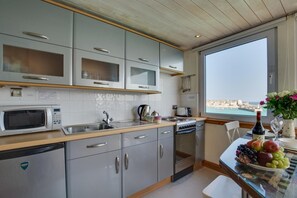 A modern kitchen with a view of the sea, stainless steel appliances, and a dining area with a fruit platter. - 1 Bed in St Ives (oc-crab03) (St Ives)
