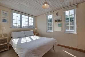 A bedroom with a bed, two bedside tables, a window, and a ceiling light. - 1 Bed in St Ives (oc-crab03) (St Ives)