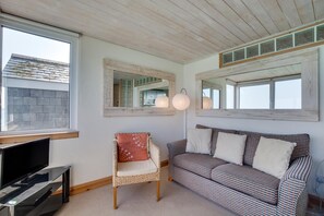 A cozy room with a television, a wicker chair, a striped sofa, and two mirrors on the walls. - 1 Bed in St Ives (oc-crab03) (St Ives)