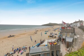 A beach with people, boats, and buildings along the shore.