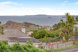 Une vue sur la côte, avec un phare, une construction située au sommet d’une colline et des immeubles résidentiels.