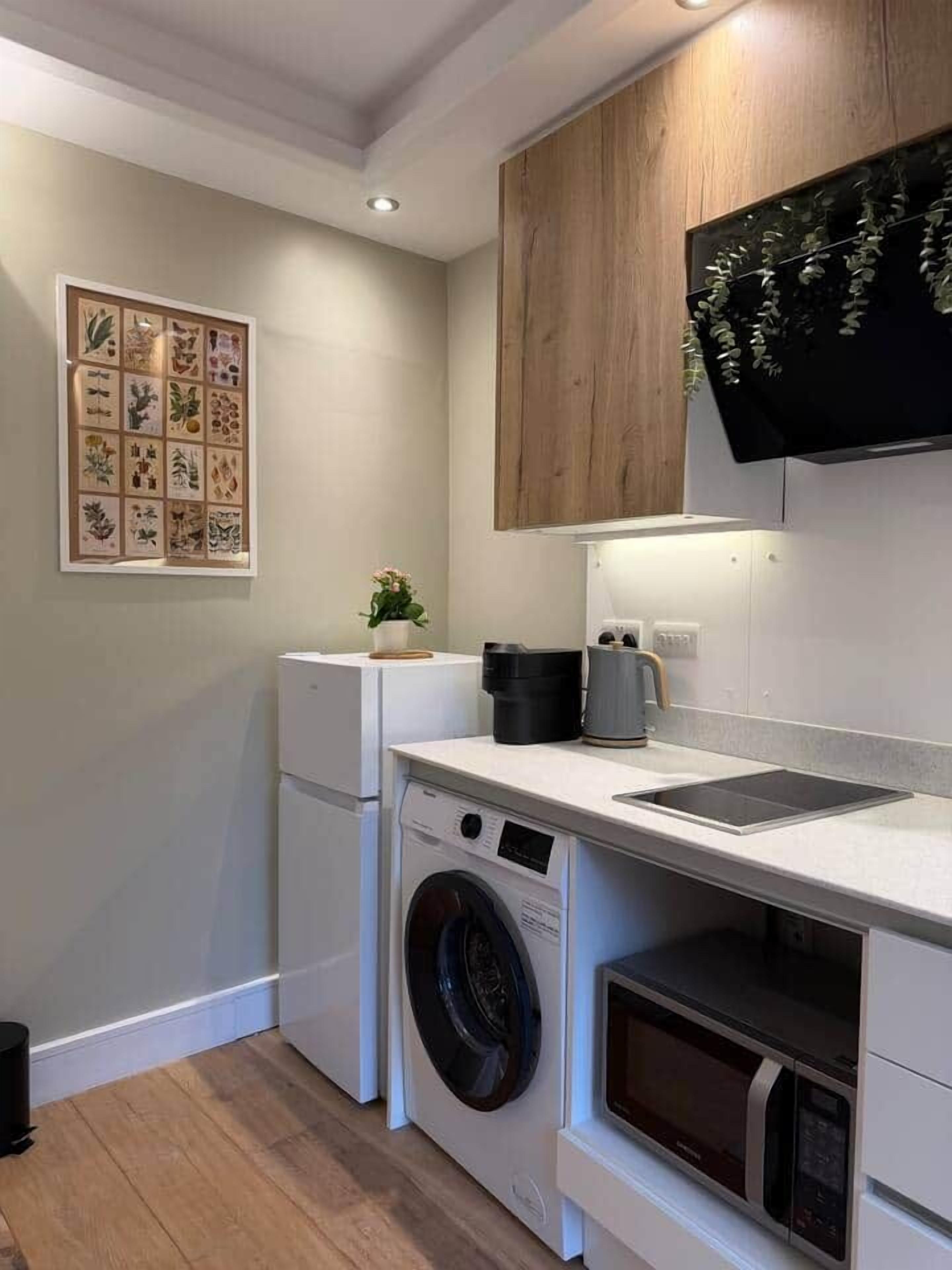A compact kitchen with a washing machine, a microwave, and a coffee maker.