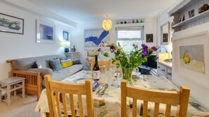 Ein modernes Wohnzimmer mit Esstisch, Holzsesseln, einer Couch und einem Couchtisch.