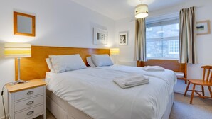 Ein Hotelzimmer mit einem großen Bett, Nachttischen, einem Schreibtisch und einem Stuhl.