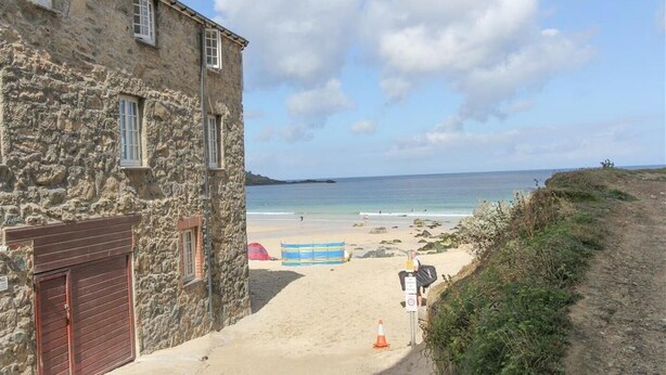 Ein Steinhaus mit einem Strand im Hintergrund.