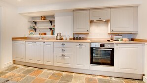 A modern kitchen with white cabinetry, a built-in oven, and a stone tile floor. - 1 Bed in St Ives (oc-salt3) (Saint Ives)