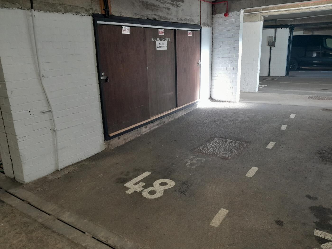 Een parkeergarage met een gesloten deur waarop 'Nee 2 Meter Kast' staat, en parkeerplaatsnummer '48'.