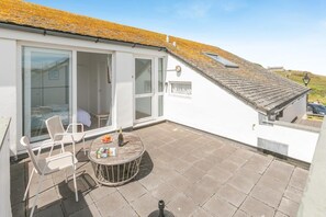Eine Terrasse mit Tisch, Stühlen und einer Champagnerflasche.