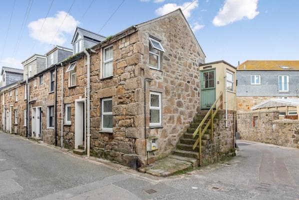A stone building with a staircase leading to the entrance, a visible door, and a window. - 2 Bed in St Ives (oc-is014a) (St Ives)