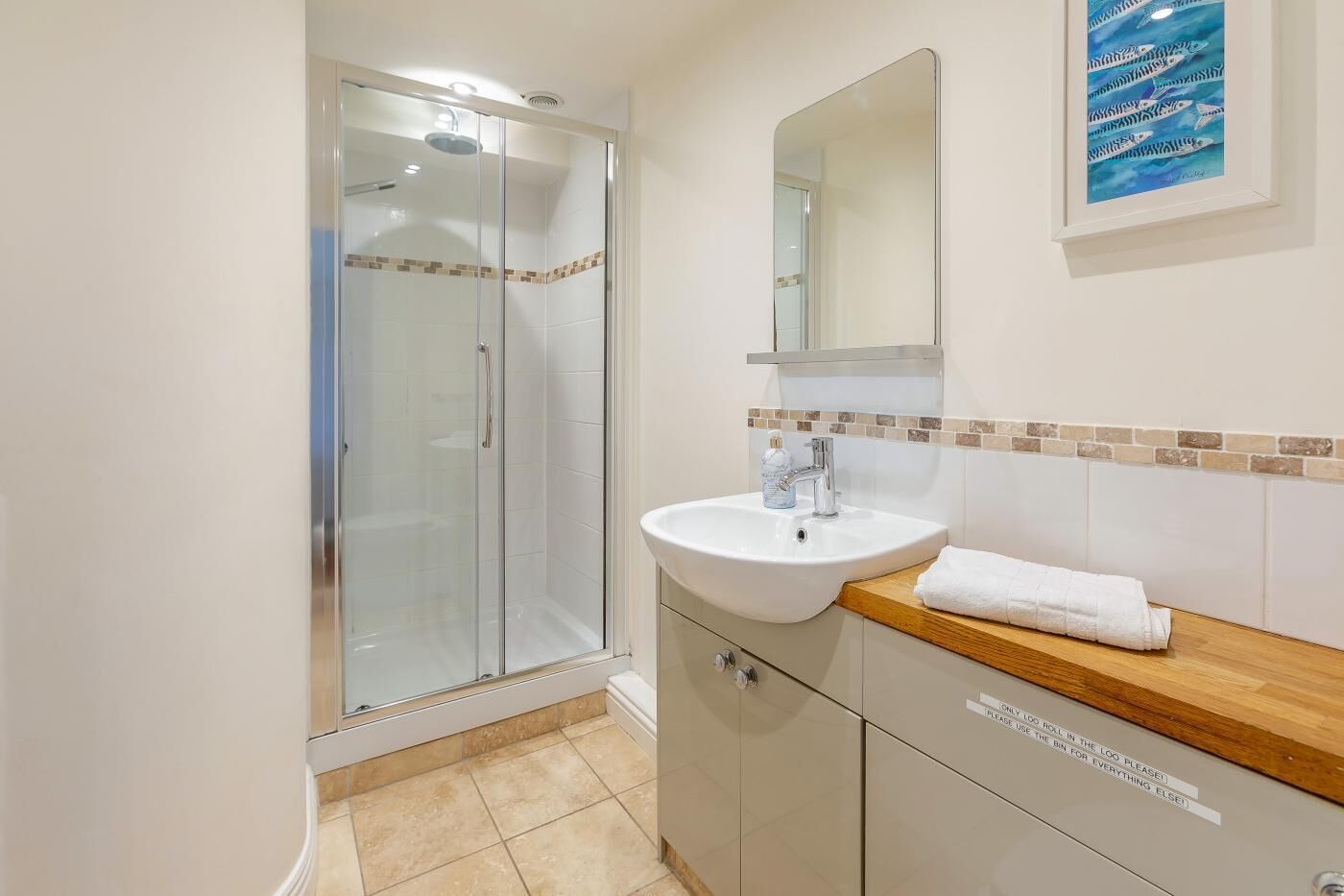 A bathroom with a glass shower enclosure, a sink with a wooden countertop, and a mirror above the sink.