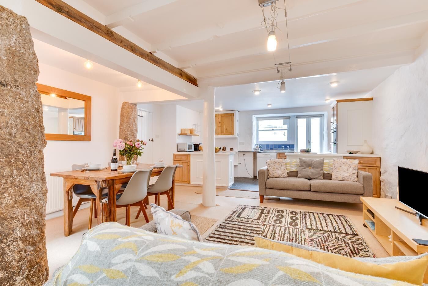 A spacious living area with a dining table, sofa, and a TV.