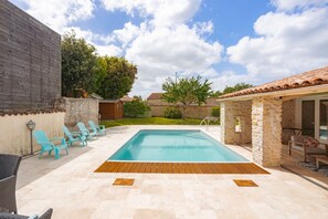 Una piscina con cubierta de madera, rodeada de muros de piedra y un edificio de ladrillo.