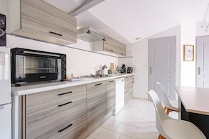 Una cocina moderna con microondas integrado, lavavajillas y comedor con mesa y sillas.
