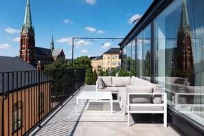 A balcony with a sofa and table, a railing, and a view of a church with two spires. - Grand House Stockholm (Stockholm)