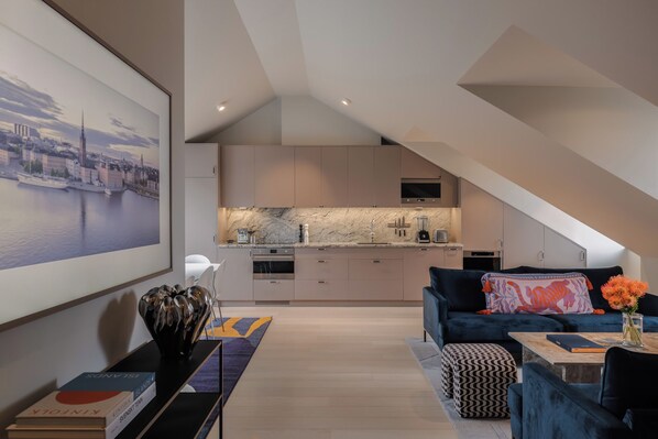 A modern loft apartment with a kitchen, living area, and a large cityscape painting. - Grand House Stockholm (Stockholm)