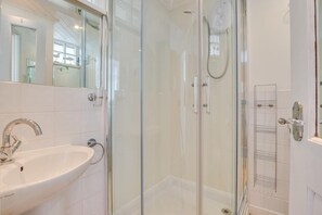 Ein modernes Badezimmer mit einer Duschkabine, einem Waschbecken und einem Spiegel.