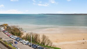 Blick auf einen Strand mit Parkplatz und einem Gebäude im Vordergrund.