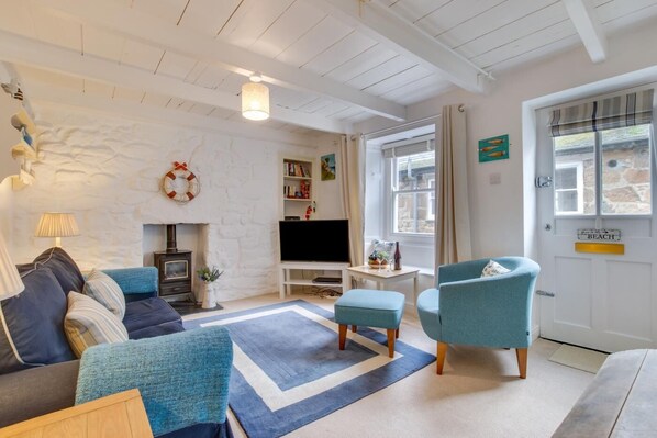 A cozy living room with a fireplace, a television, and a bookshelf. - 2 Bed in St Ives (oc-tee009) (St Ives)