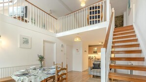 Spazioso appartamento in stile loft con zona pranzo, cucina e una scala in legno.