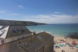 A coastal building with a sloped roof, a beach in the background, and a clear sky. - 2 Bed in St Ives (oc-nic24) (Saint Ives)